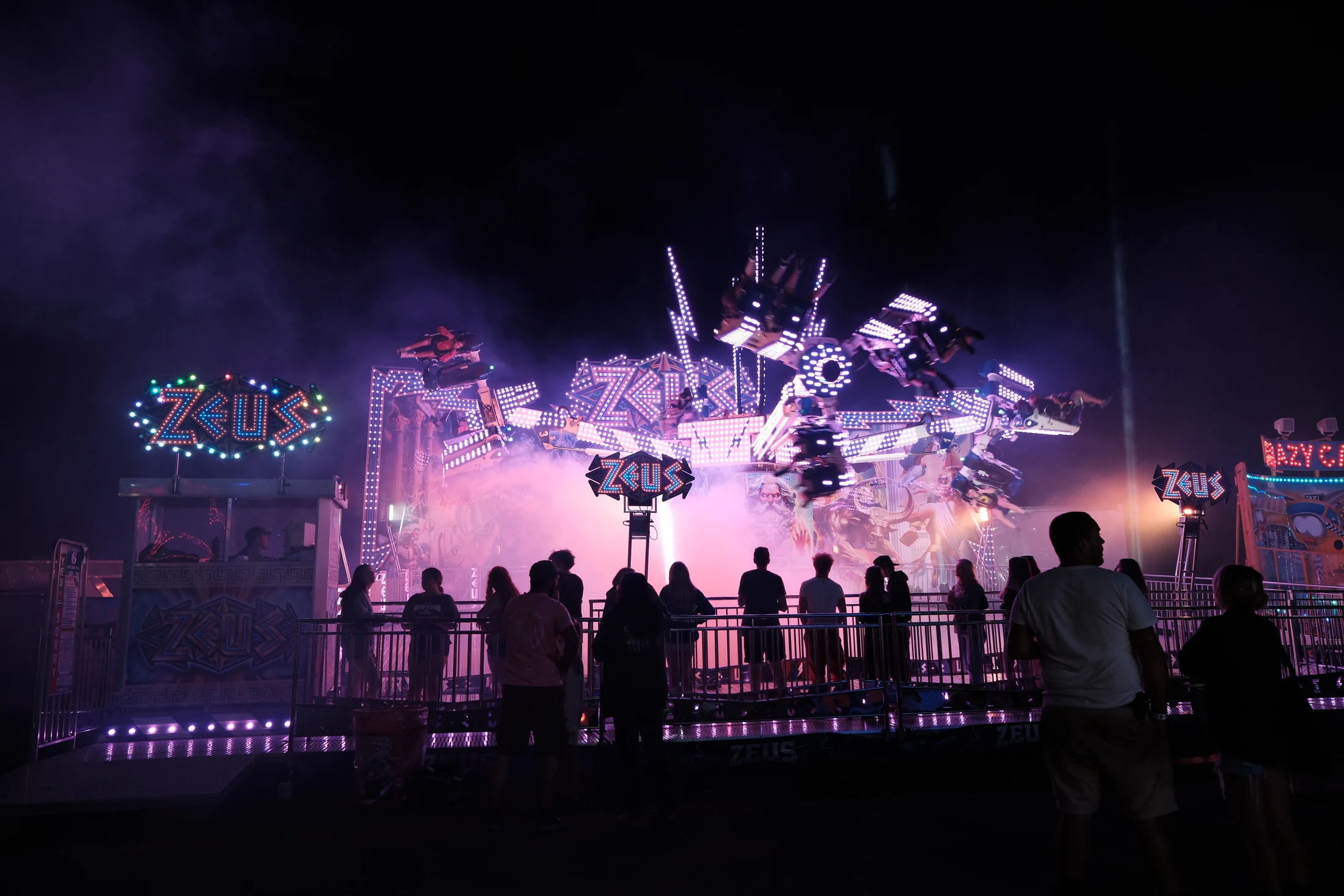 The midway comes alive after dark as fairgoers watch the brightly lit Zeus ride at the Delaware County Fair.
